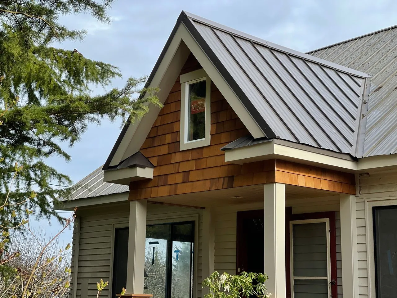 Gable end with cedar shingles, a standing-seam metal roof and a covered porch