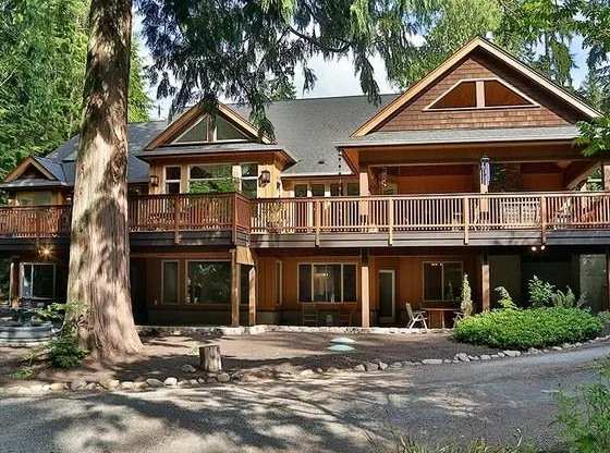 Home with cedar shingle gables and a long deck under tall evergreens