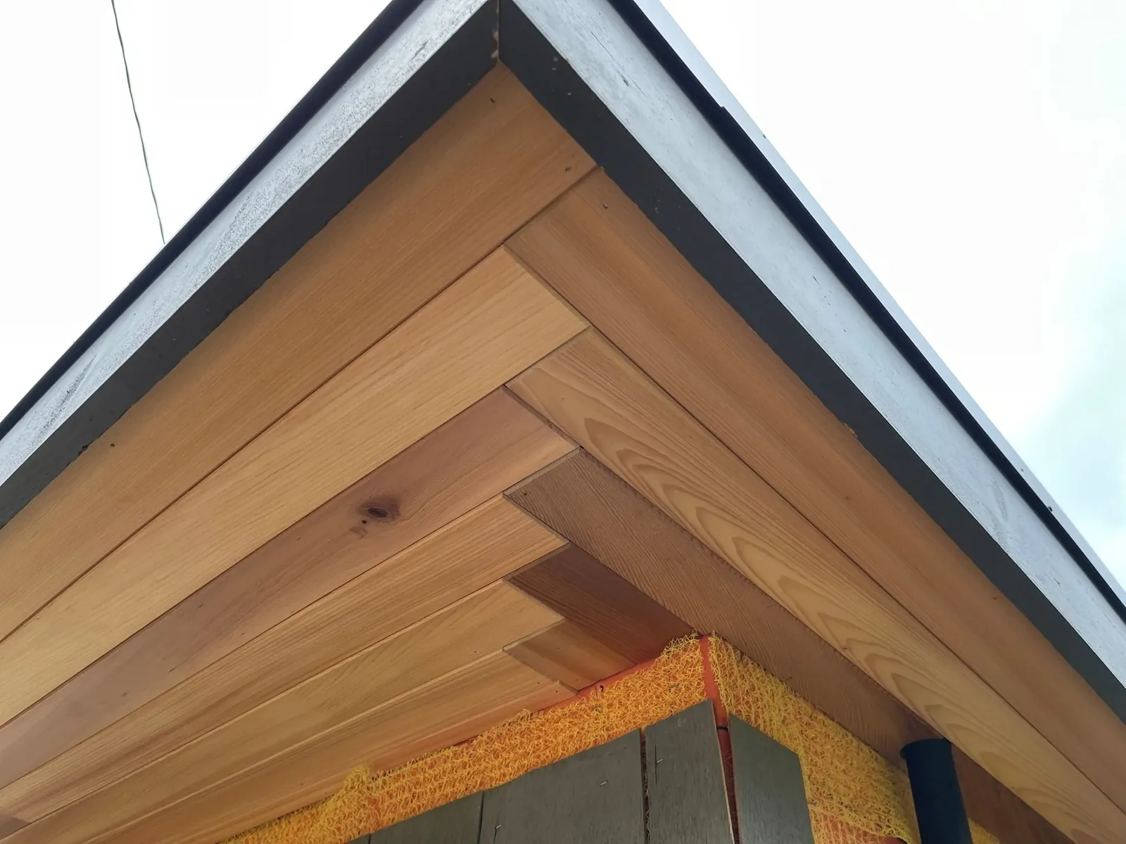 Cedar soffit boards meeting at a gable peak under a dark fascia