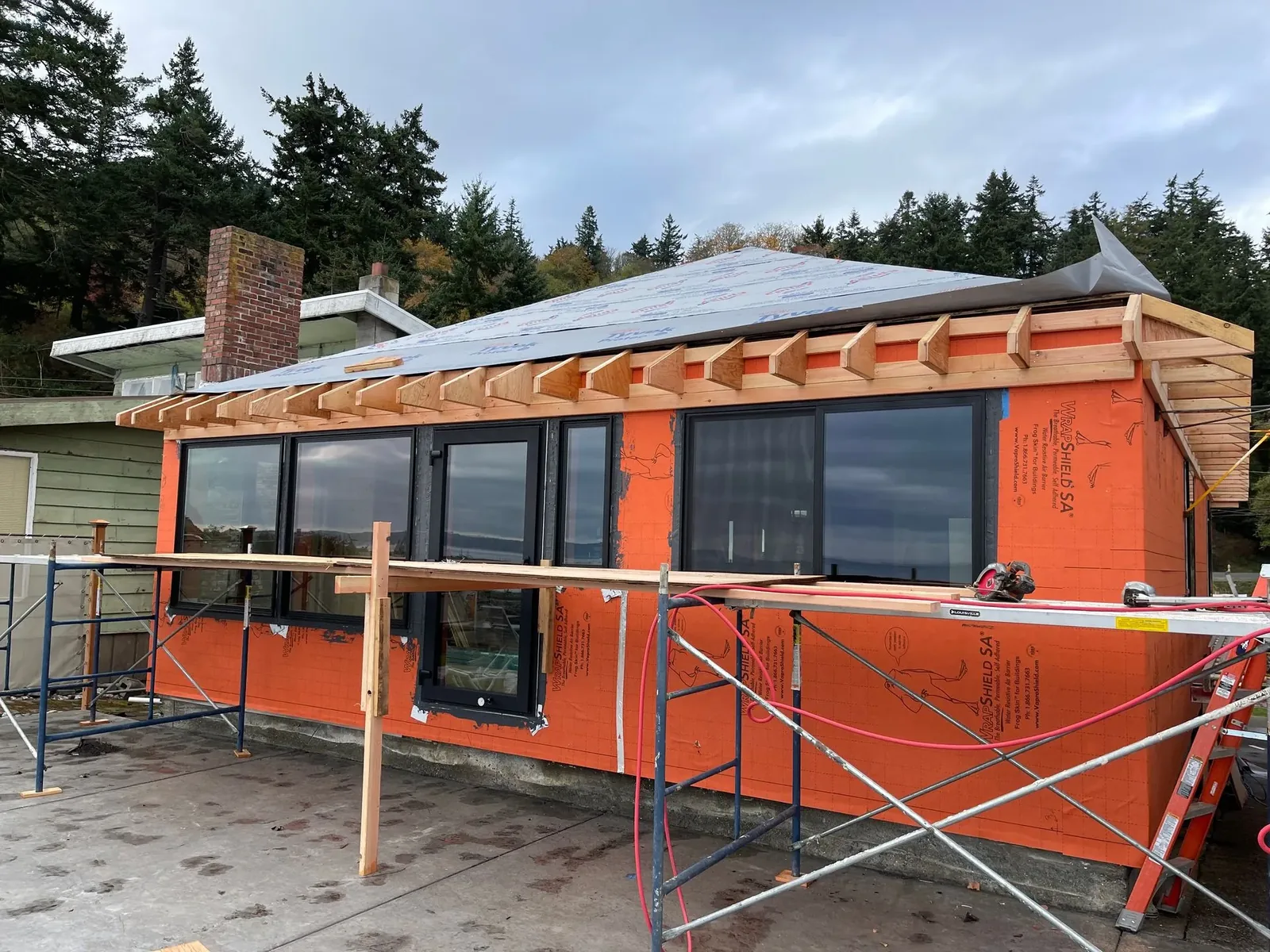 Cottage remodel with house wrap, new windows and new rafter tails under scaffolding