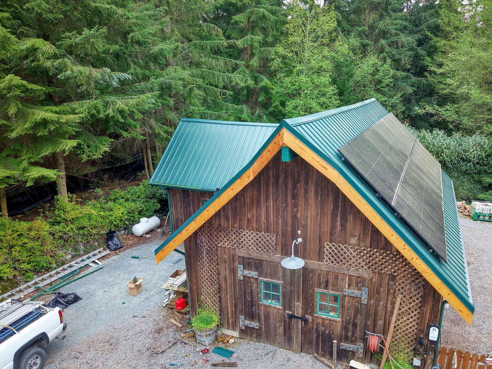 Drone view of a cedar barn with a new green metal roof, cedar fascia and solar panels