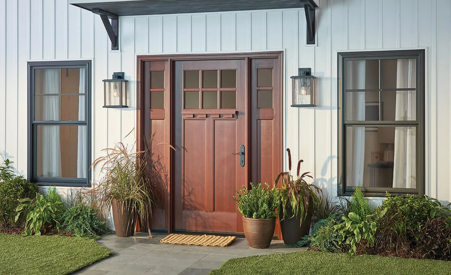 New wood entry door with sidelights on a home with white board-and-batten siding