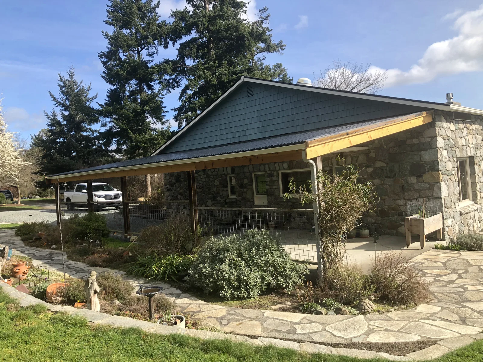 Stone-faced home on Whidbey Island with a new metal-roofed porch cover on fresh cedar beams
