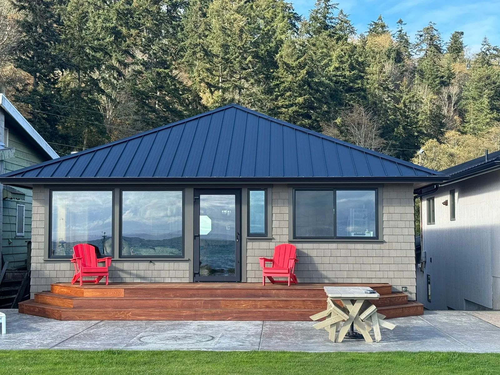 Finished cottage with a standing-seam metal roof, shingle siding and a glass entry door