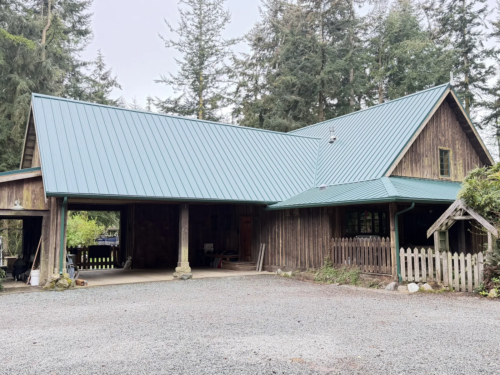 Finished green standing-seam metal roof over a cedar home and its carport