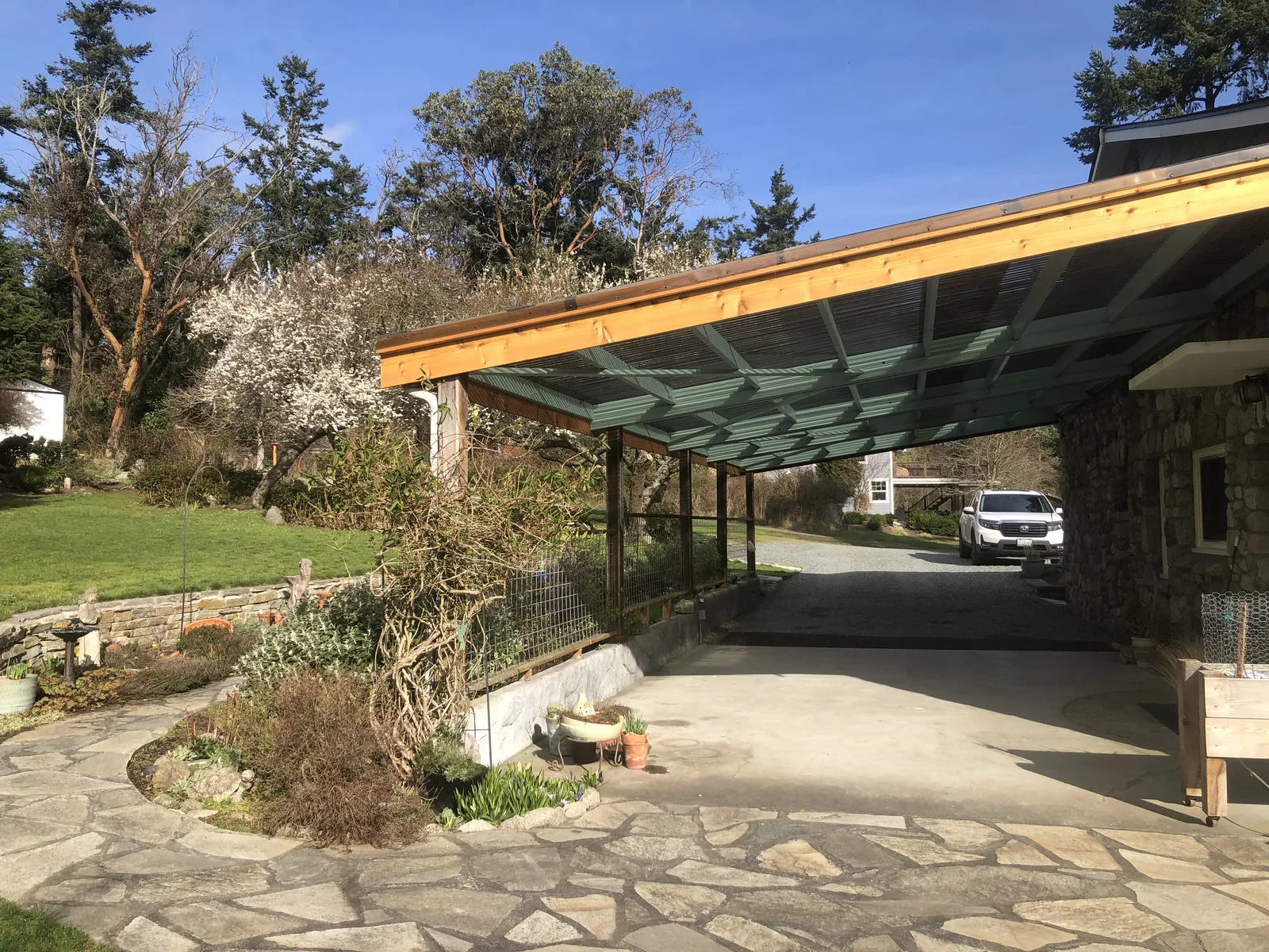 Finished patio cover with translucent roof panels on a new wood frame beside a stone home