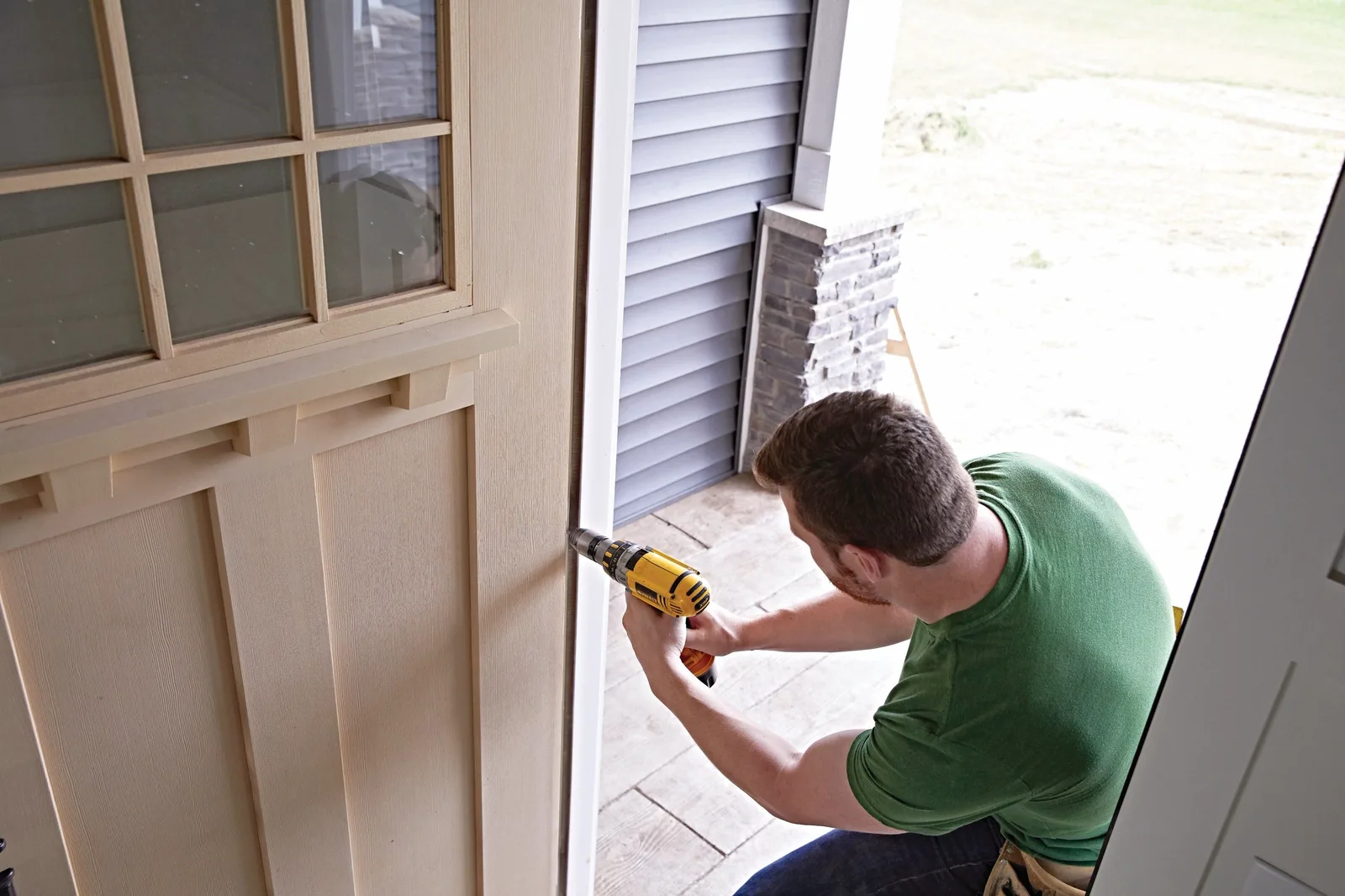 Carpenter drilling into a new exterior door jamb during installation