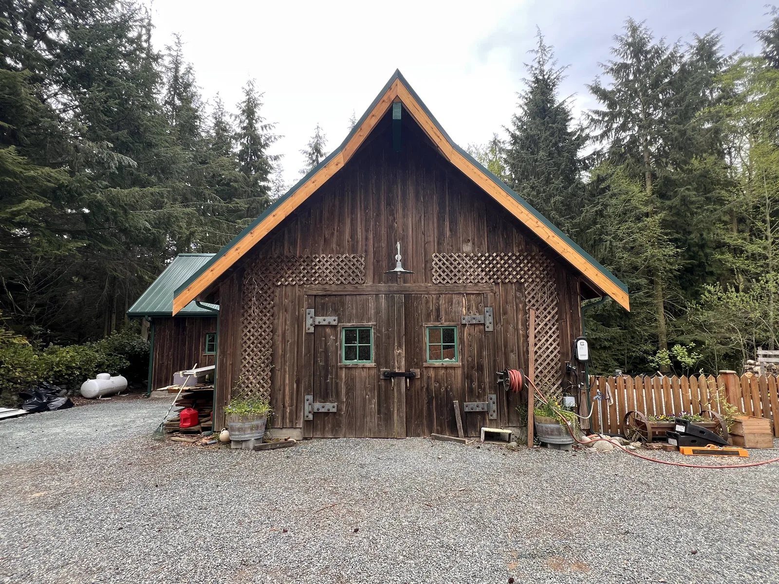 Cedar barn with a new dark green standing-seam metal roof and fresh cedar rake trim