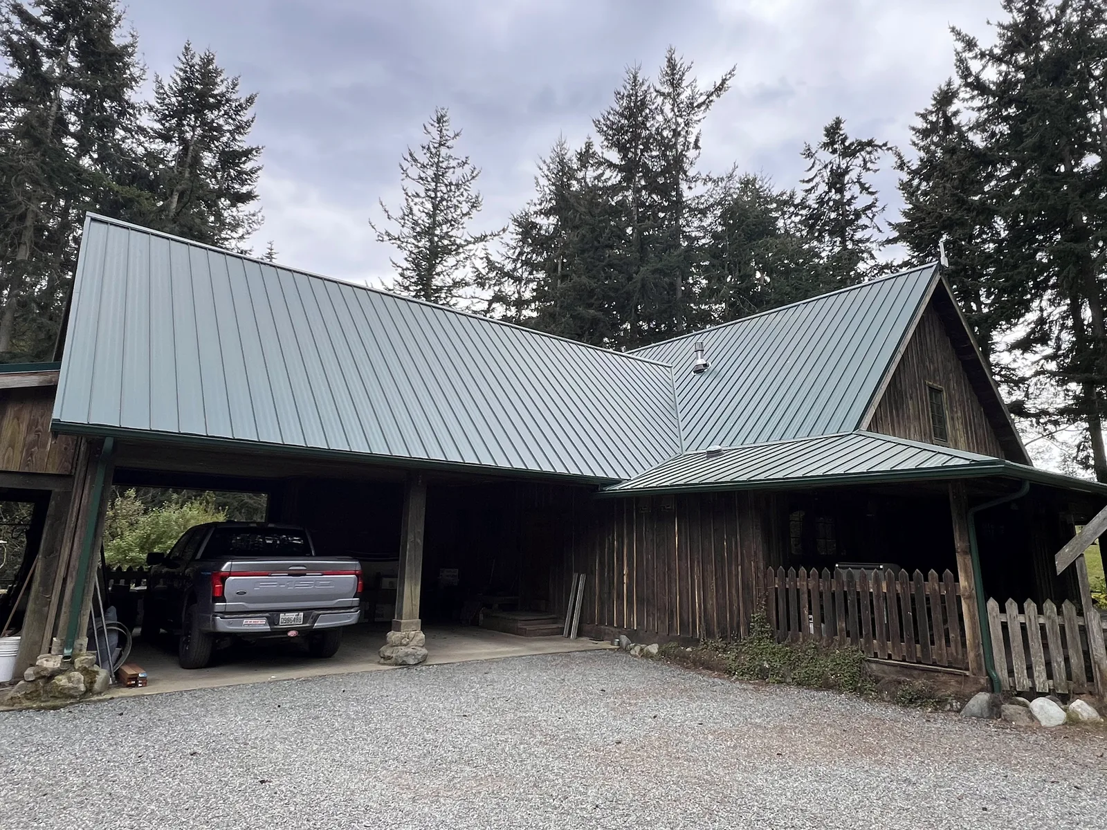 New grey-green standing-seam metal roof over a Whidbey Island home and its attached carport