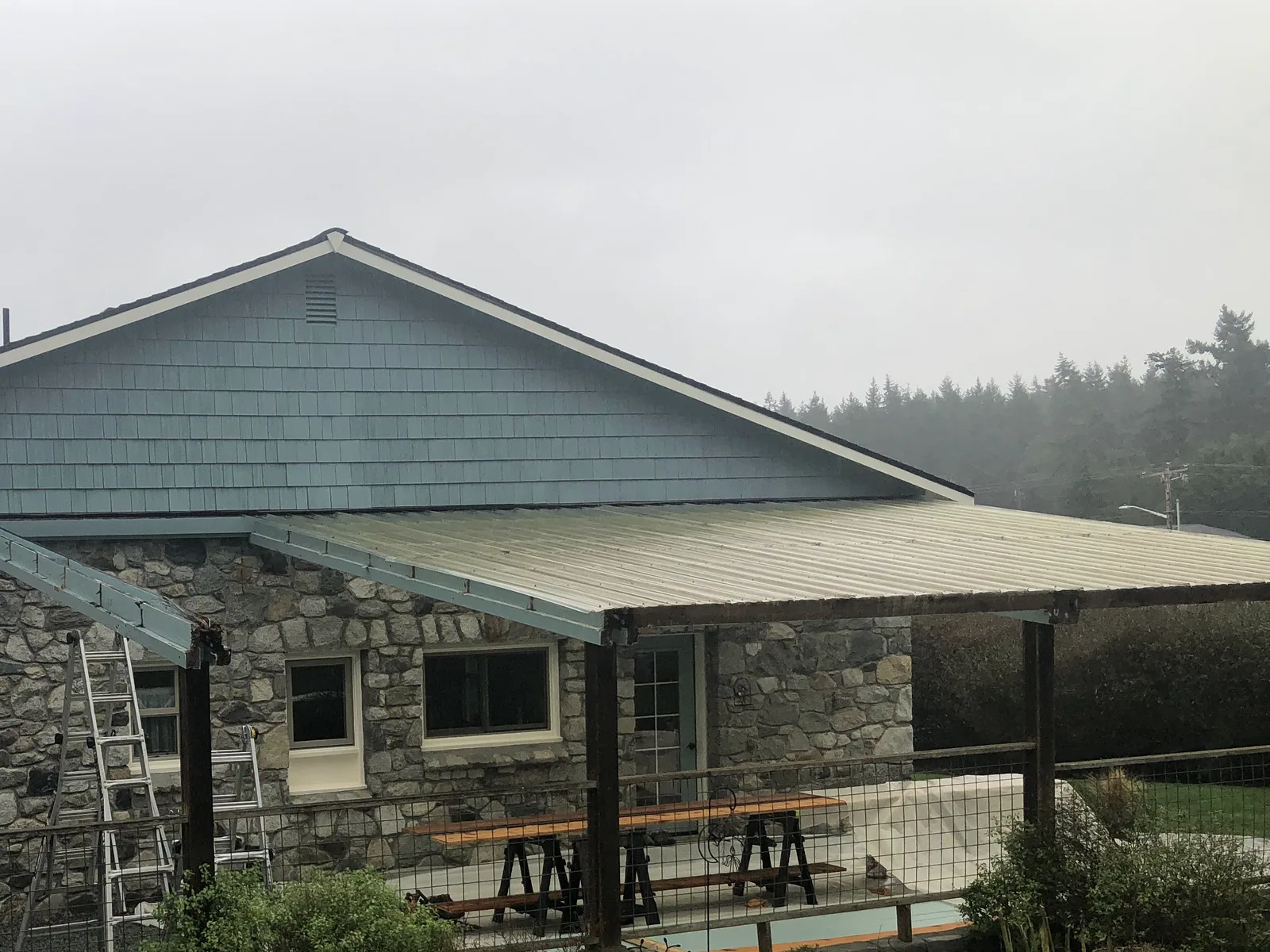 New metal roof panels on a stone home's patio cover on a foggy Whidbey Island morning
