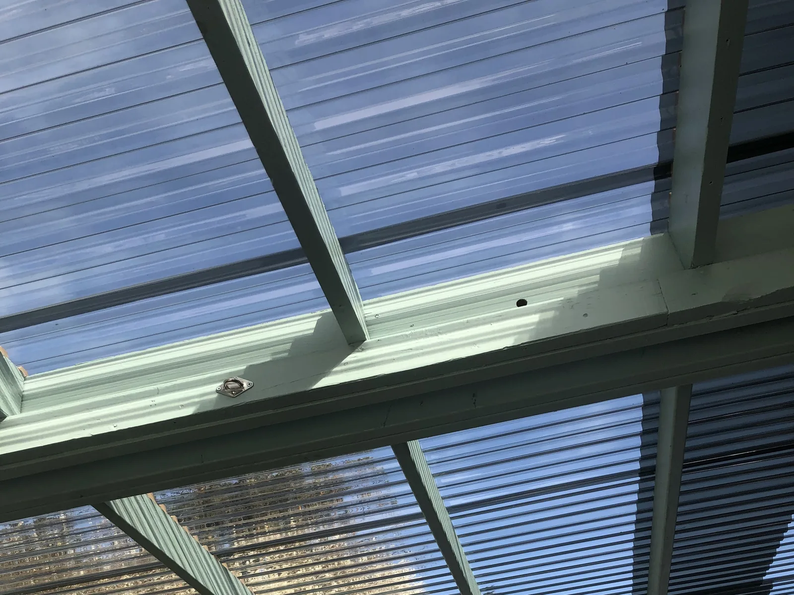 Blue-tinted patio cover panels on a new frame, seen from below