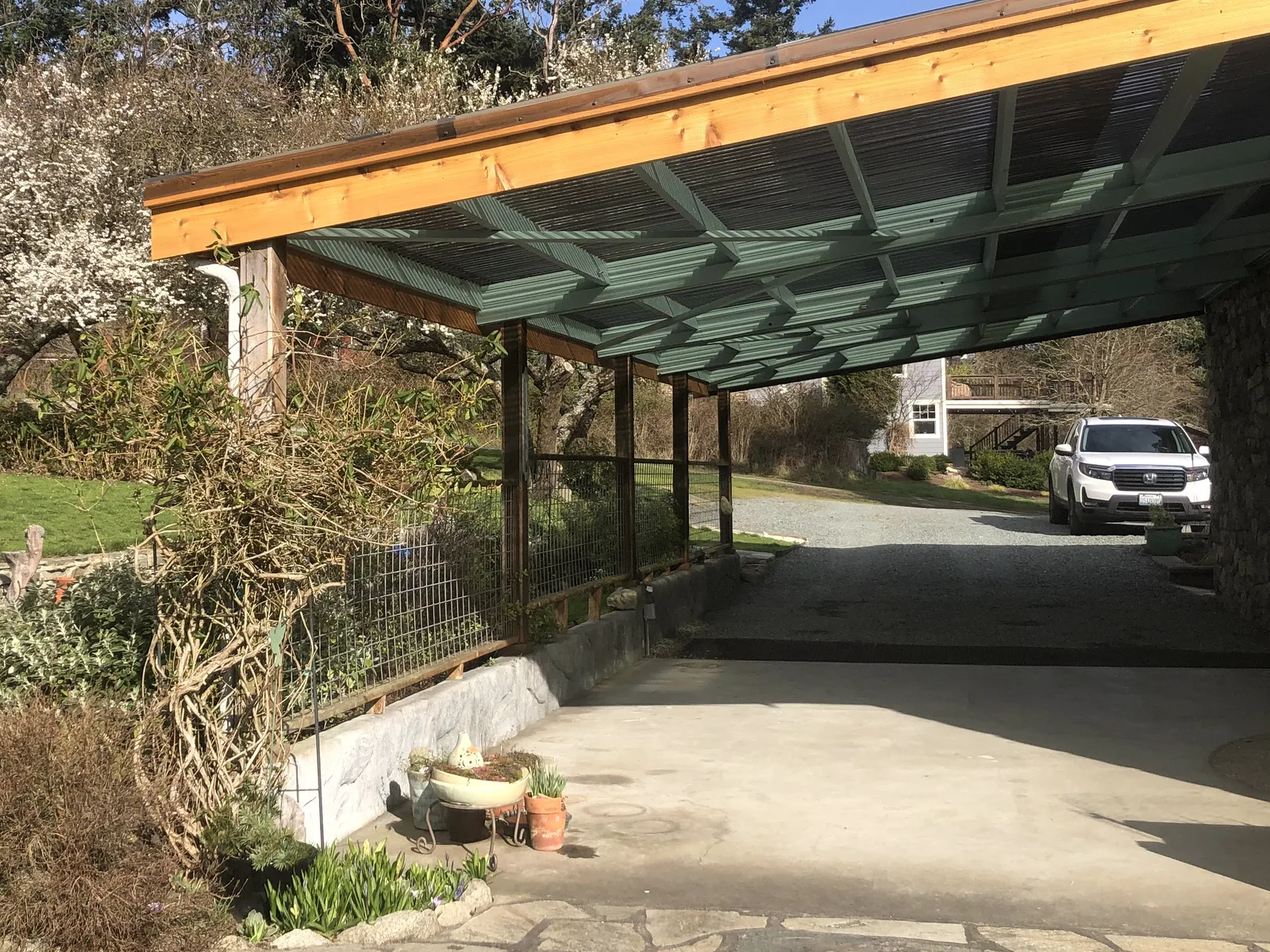 Long covered patio with translucent roof panels on a new timber frame beside a stone home