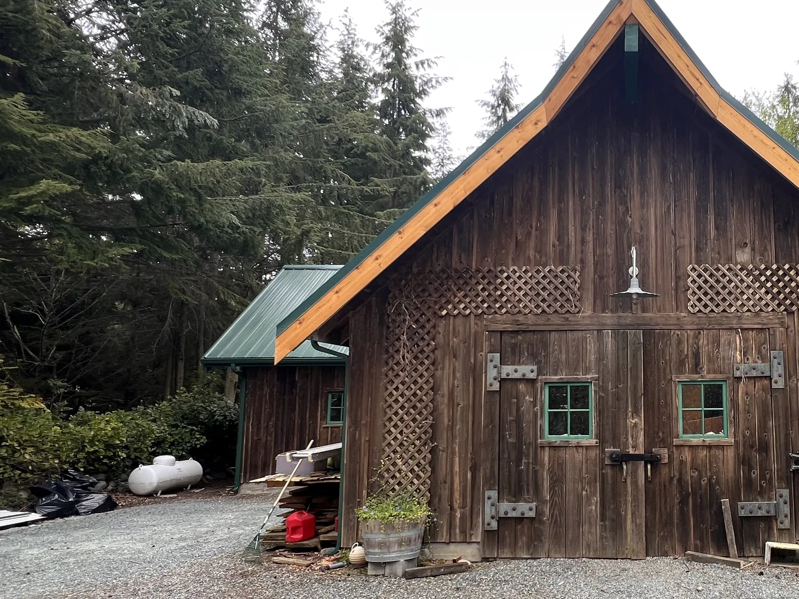 Dark green standing-seam metal roof and new cedar trim on a cedar barn
