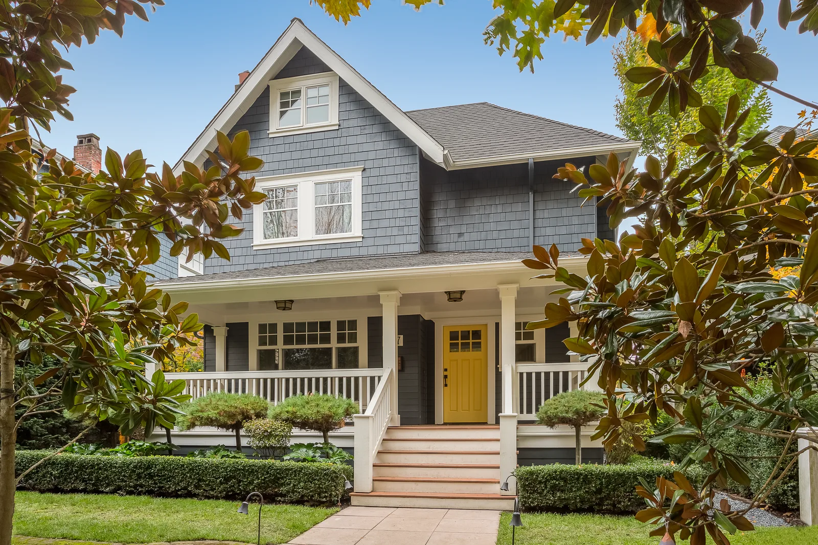 Dark blue-grey craftsman home with a covered porch and a grey roof