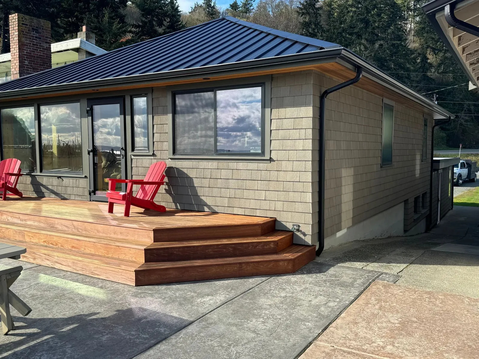 Shingle-sided cottage with a black gutter and downspout and new deck steps