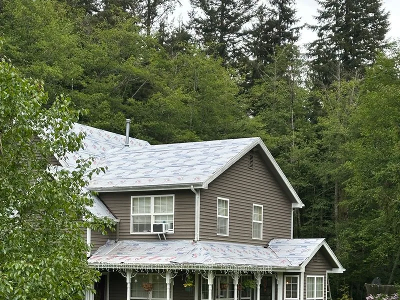 Two-story grey farmhouse with a light grey roof and a covered front porch