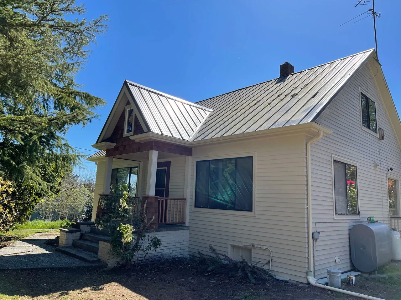 White farmhouse with a standing-seam metal roof and a covered front porch