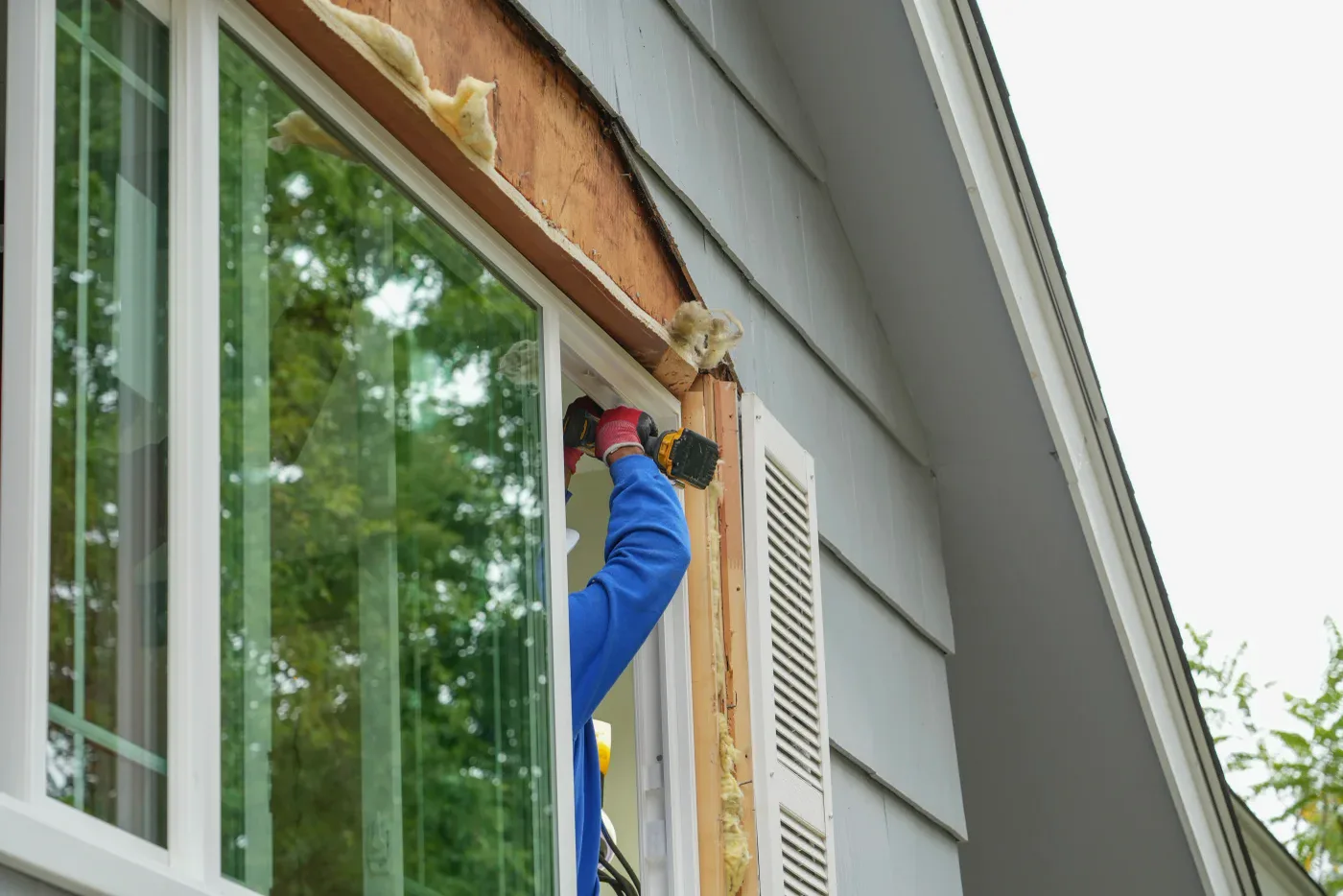 Installer fastening a new window into the opening from outside the house